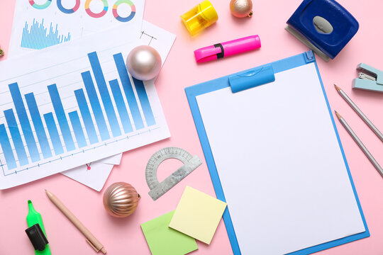 Blank clipboard with stationery, diagrams and Christmas balls on pink background