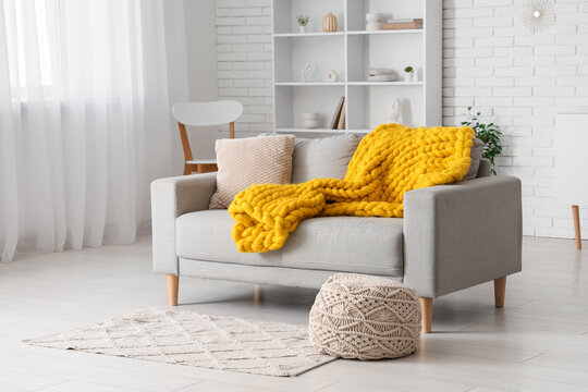 Fototapeta Modern interior of living room with stylish grey sofa, pouf and yellow knitted plaid