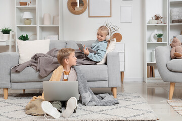 Little boy and girl with plaids using gadgets at home