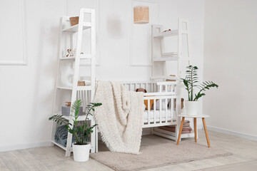 Interior of light children's bedroom with crib, toys and houseplants