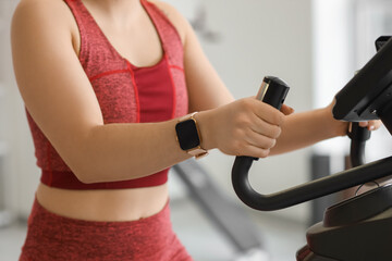 Sporty woman on exercising bike at gym, closeup