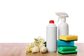 Bottles of detergents with cleaning sponges and spring flowers on table against white background