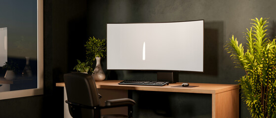 White curved screen computer and plant on wooden table with swivel chair near window in dim lit room.