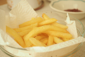 Crispy golden fries served in a glass bowl on a table