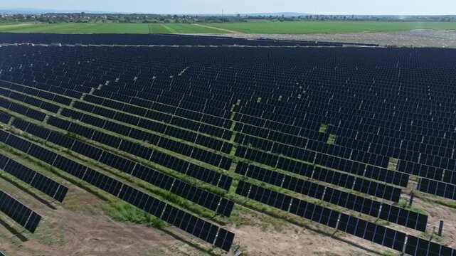 Aerial view of solar farm panels under sunny skies, showcasing renewable energy