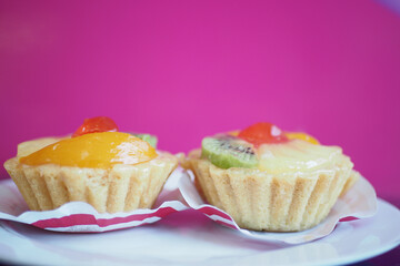 Colorful fruit tarts on a bright pink background
