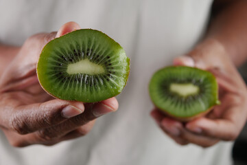 Fototapeta premium Freshly cut kiwi halves held in hands for display