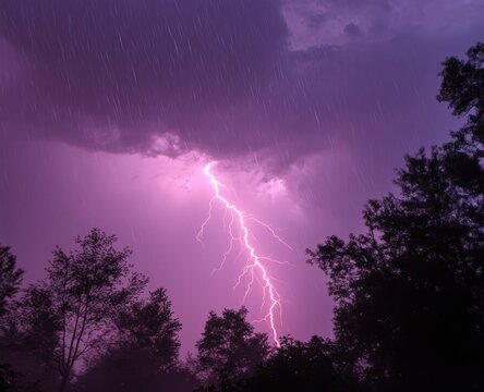 Intense lightning bolt striking down during a rainy storm with dark silhouetted trees under a dramatic purple sky - Powered by Adobe