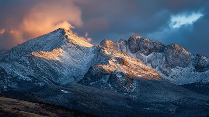 Snowy mountain range at sunrise with golden light on peaks and clouds against a dark blue sky - Powered by Adobe