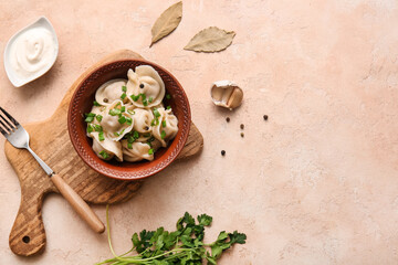 Bowl of delicious boiled dumplings with green onion and sour cream on beige background