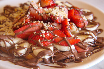 A delicious plate of dessert topped with strawberries, bananas, and chocolate