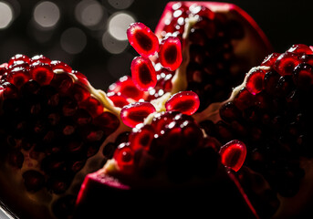 A dramatic macro close-up of an opened pomegranate, showcasing the jewel-like, translucent red seeds (arils).