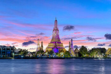 Naklejka premium 26 November 2025 Beautiful Sunset colours of Thai Temple Wat Arun on Chao Phraya River in BKK Bangkok Thailand. The magic colourful neon light display on the temple at sunset is magical.