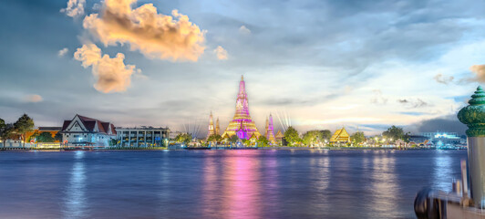 Naklejka premium 26 November 2025 Beautiful Sunset colours of Thai Temple Wat Arun on Chao Phraya River in BKK Bangkok Thailand. The magic colourful neon light display on the temple at sunset is magical.