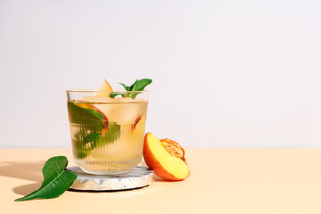 Glass of fresh peach lemonade with mint on orange table against grey background
