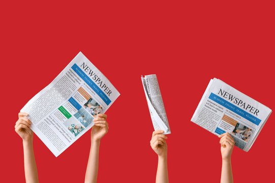 Female hands with newspapers on red background