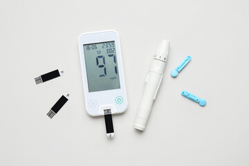 Obraz premium Glucometer, lancet pen, test strips and disposable needles on grey background. Diabetes concept
