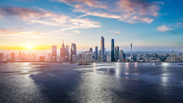 Wet asphalt road and city skyline with modern buildings at sunrise in Guangzhou