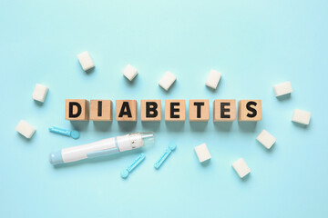 Word DIABETES with lancet pen, sugar and test strips on blue background