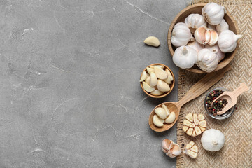 Wooden bowls with fresh garlics and peppercorns on grey background