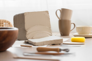 Clay block and pottery tools on table in home studio, closeup