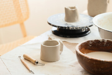 Clay cup and pottery tools on table in home studio, closeup