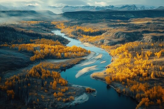 Aerial view of a winding river cutting through golden autumn forest and rolling hills toward snow-capped mountains under a serene dramatic sky - Powered by Adobe