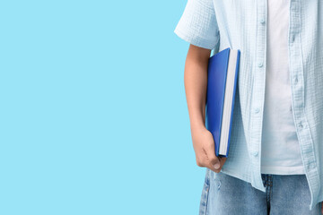 Cute little girl holding book on blue background