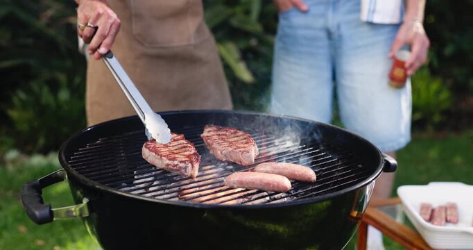 Barbecue, cooking and hands with people in backyard of home for reunion or social gathering. Food, meal preparation and tongs with bbq meat on grill for cookout, get together or hangout outdoor