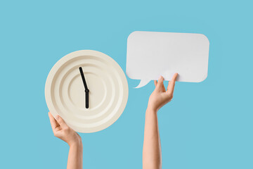 Female hands holding wall clock with blank speech bubble on blue background
