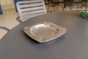 An empty tin cigarette ashtray on the table