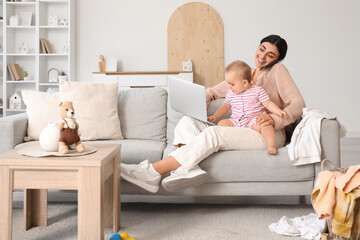 Busy young business mother with laptop, mobile phone and cute little baby at home