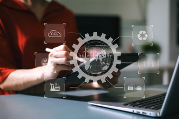 Woman using futuristic interface with smart tech and mobile to manage ESG, clean energy, and sustainability data. in office