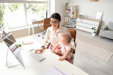 Young business mother with computer and cute little baby working at home