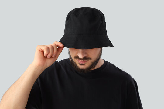 Handsome young man in stylish bucket hat on grey background