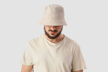 Handsome young man in stylish bucket hat on grey background