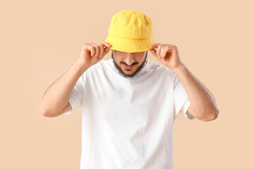 Handsome young man in stylish bucket hat on beige background