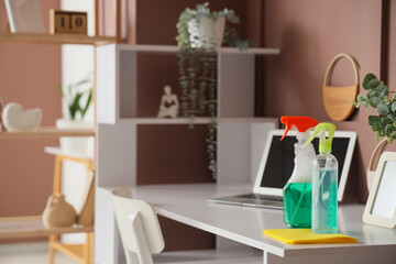 Bottles of detergent and rag on desk in home office, closeup