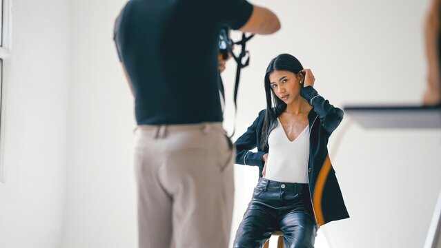 Professional photographer taking pictures of beautiful fashion model posing in modern photo studio - Powered by Adobe