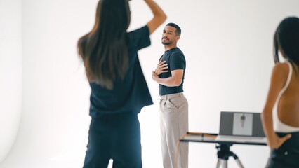 Photographer and assistants working with male model during photoshoot in modern studio with white background