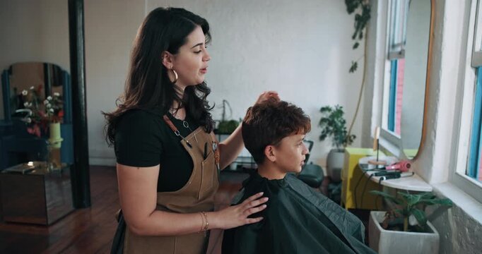 Salon, hairdresser and child with cape, talking and hair maintenance with equipment or consultation. Hairstylist, appointment and woman with boy for haircut, grooming and process for hairstyle