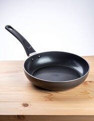 A black nonstick frying pan resting on a wooden countertop, featuring a smooth cooking surface and modern ergonomic handle.