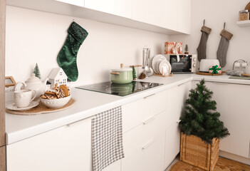 Interior of light kitchen with Christmas tree, socks and counters