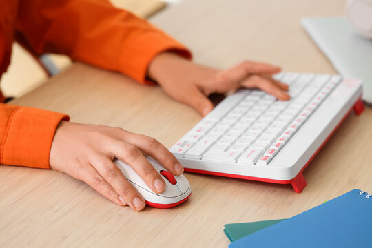 Hands of woman using computer mouse and keyboard at table in office