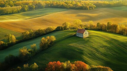 stone cottage atop sunlit rolling green hills surrounded by autumn trees and golden cultivated fields, peaceful serene rural landscape