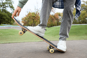 Obraz premium Legs of young man with skateboard in park, closeup