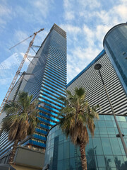 Modern skyscraper under construction alongside blue glass building in city