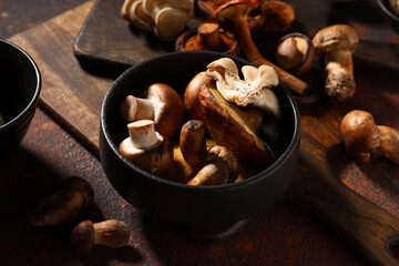 Fototapeta premium Bowl with different fresh mushrooms on red grunge background