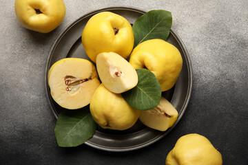 Plate with sweet ripe quinces and leaves on grunge background