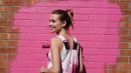 Woman Paints Brick Wall With Pink Paint Roller, Bright Sunny Day - Powered by Adobe